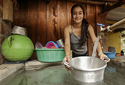 Woman holding a bucket under a water spigot