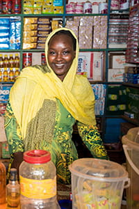 Woman from Sudan standing in front of products on shelves